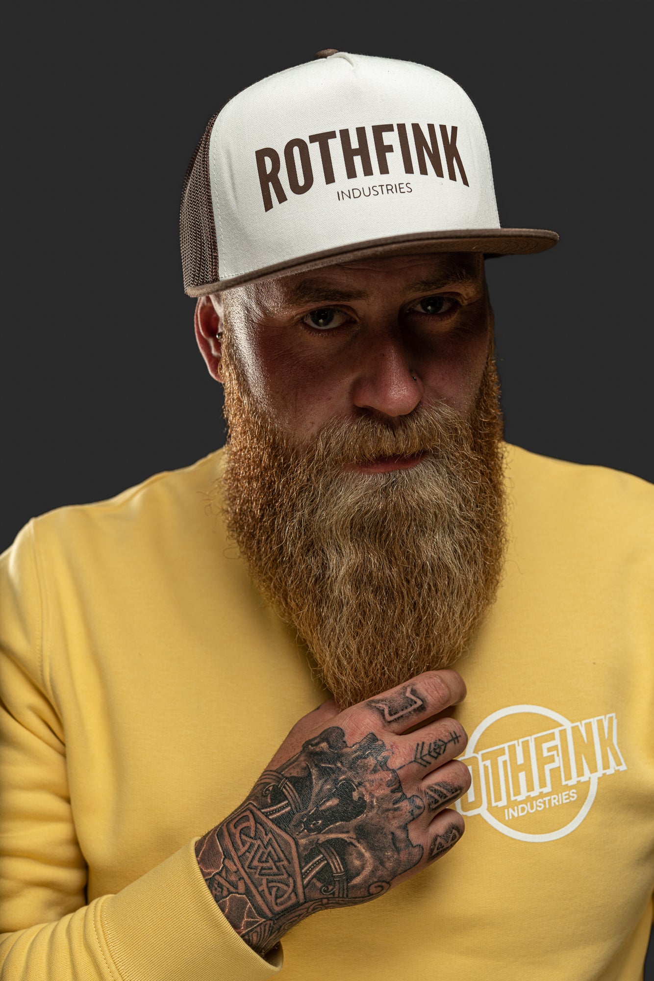 Man wearing a white cap and yellow sweatshirt with 'ROTHFINK' branding on a dark background