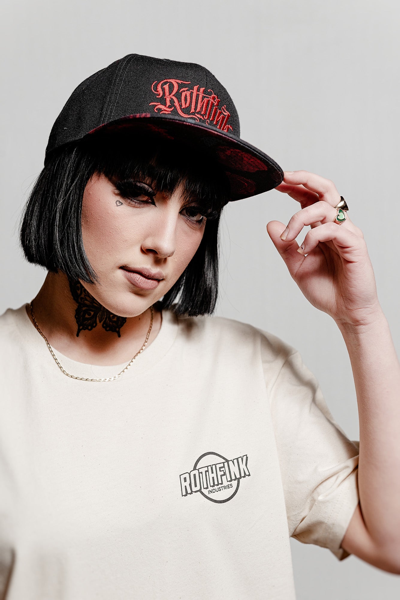 Person wearing a black cap with 'Rothfink' logo and a matching t-shirt on a plain background